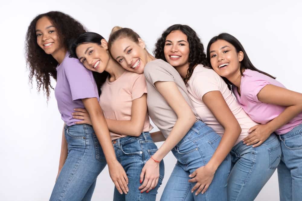 cheerful multiethnic women hugging posing over whi SZYRCT3