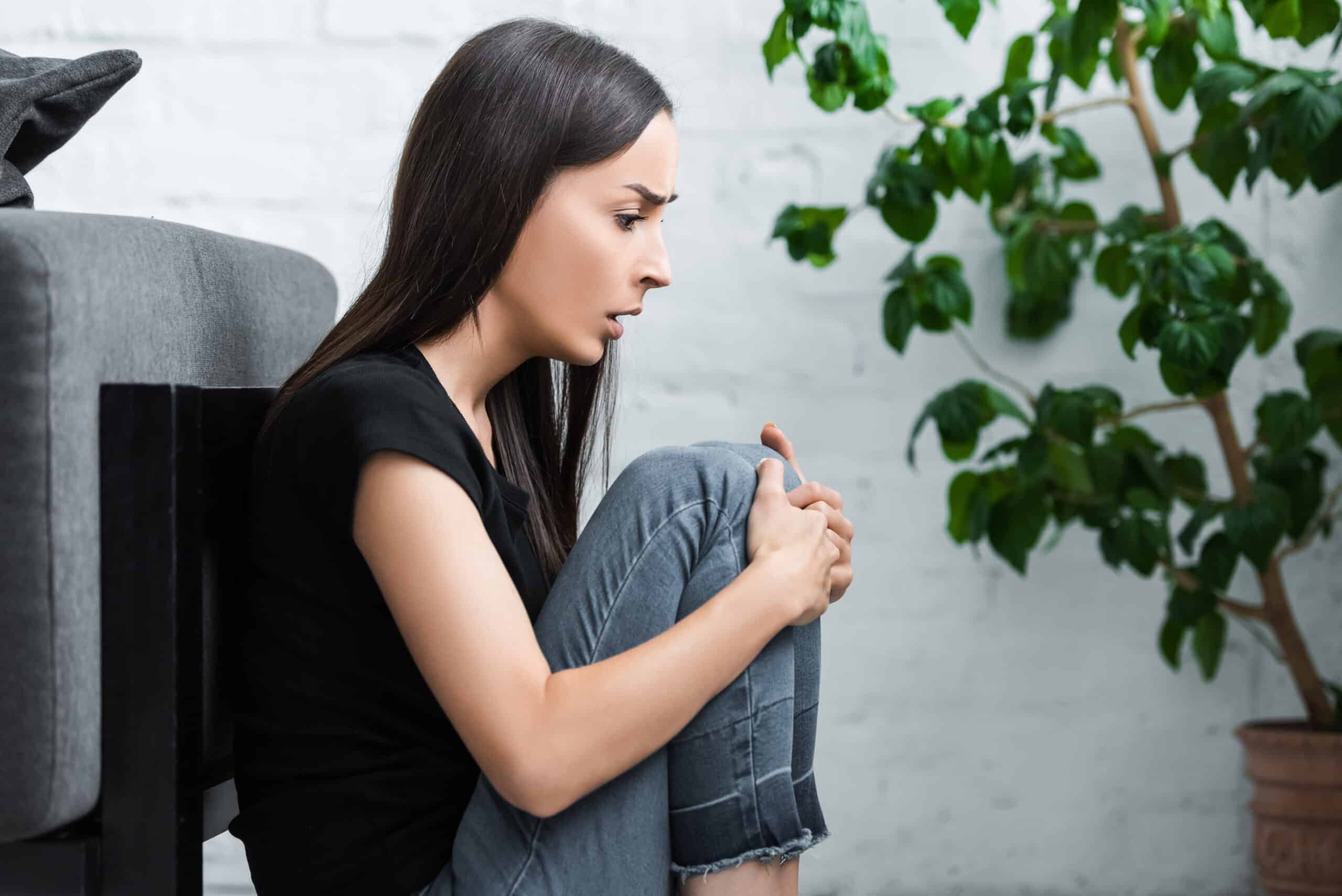 young woman sitting on floor at home and suffering 35LBR67 scaled